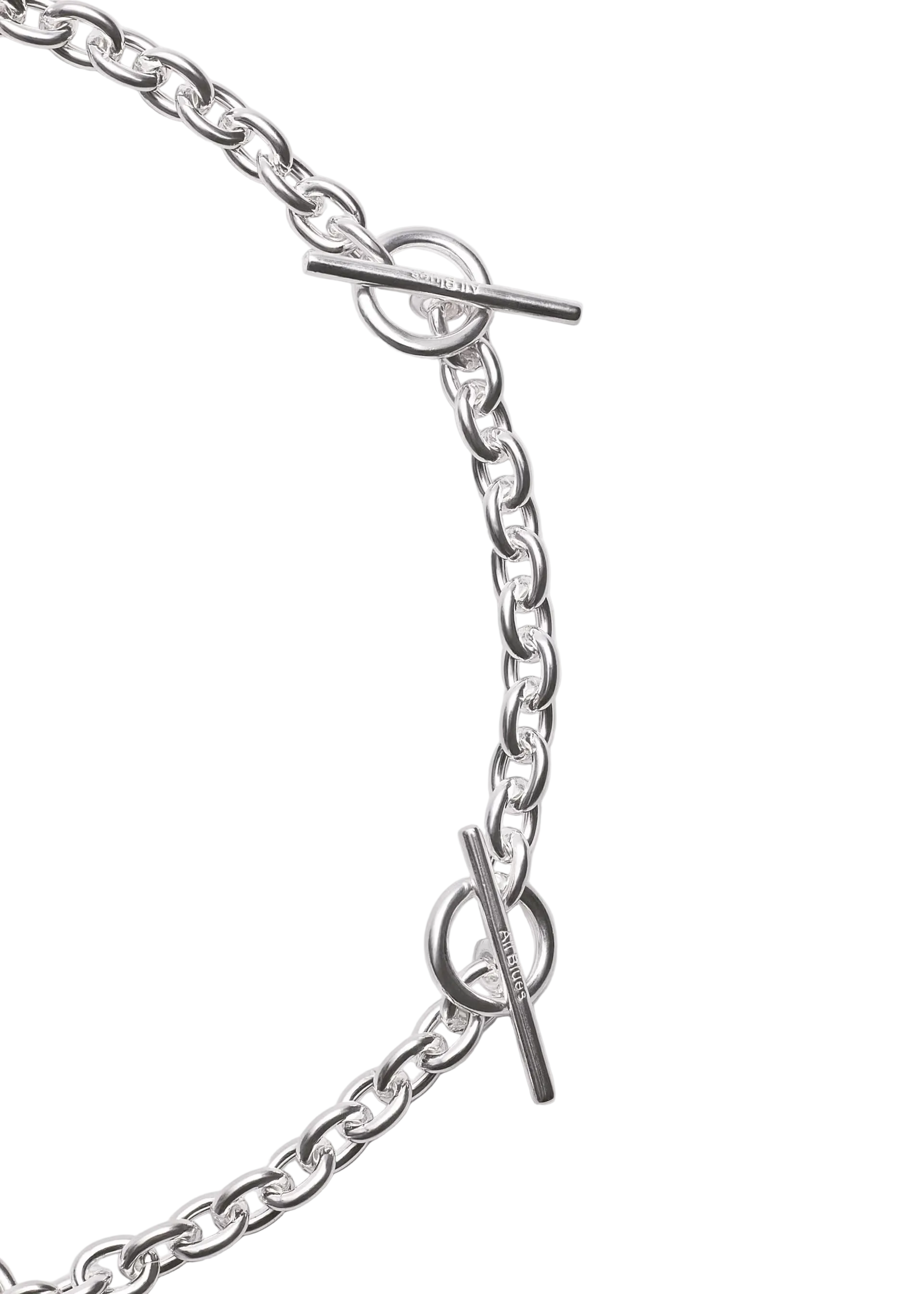 Close-up of a silver chain necklace with toggle clasp details on a light gray background.