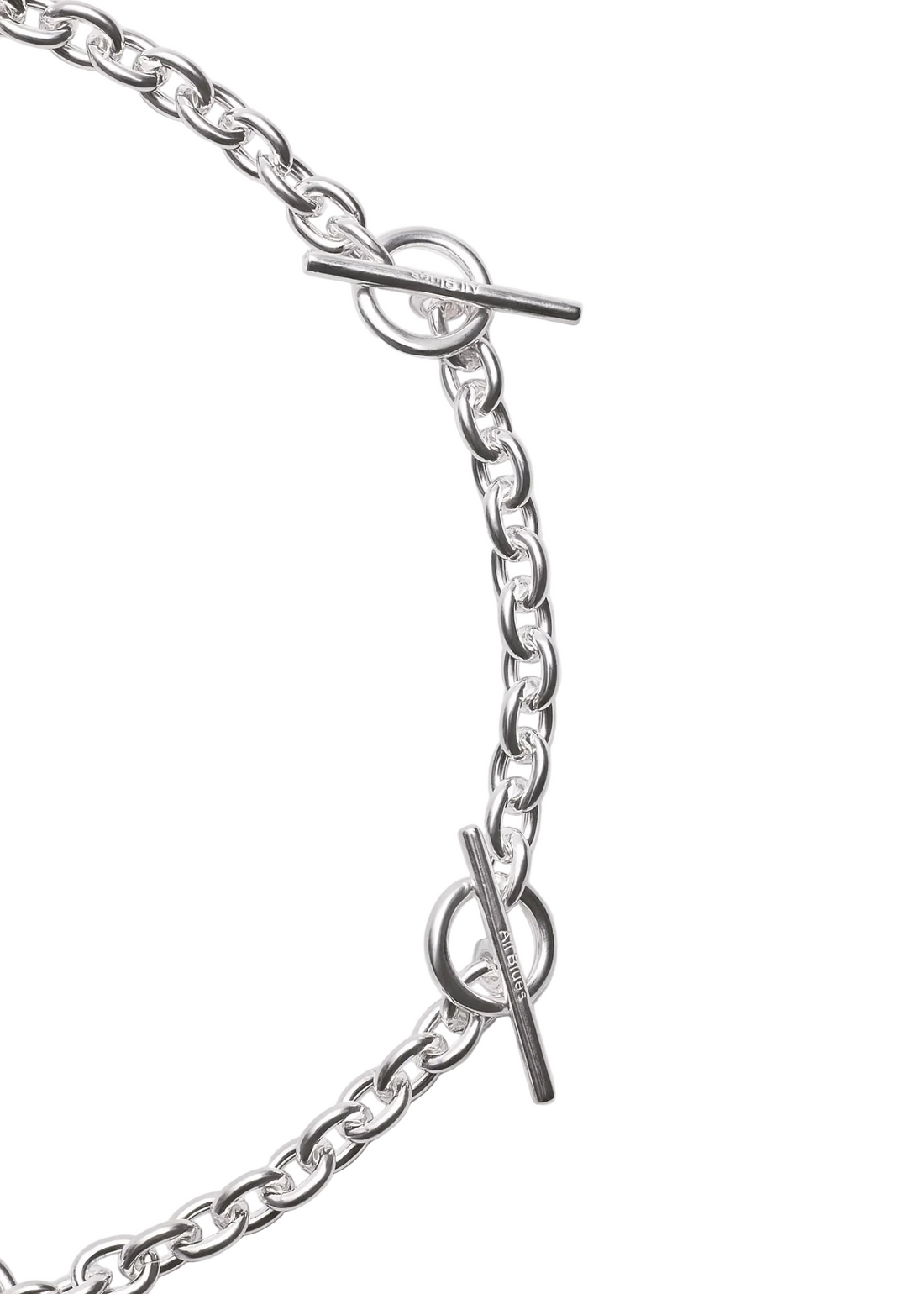 Close-up of a silver chain necklace with toggle clasp details on a light gray background.