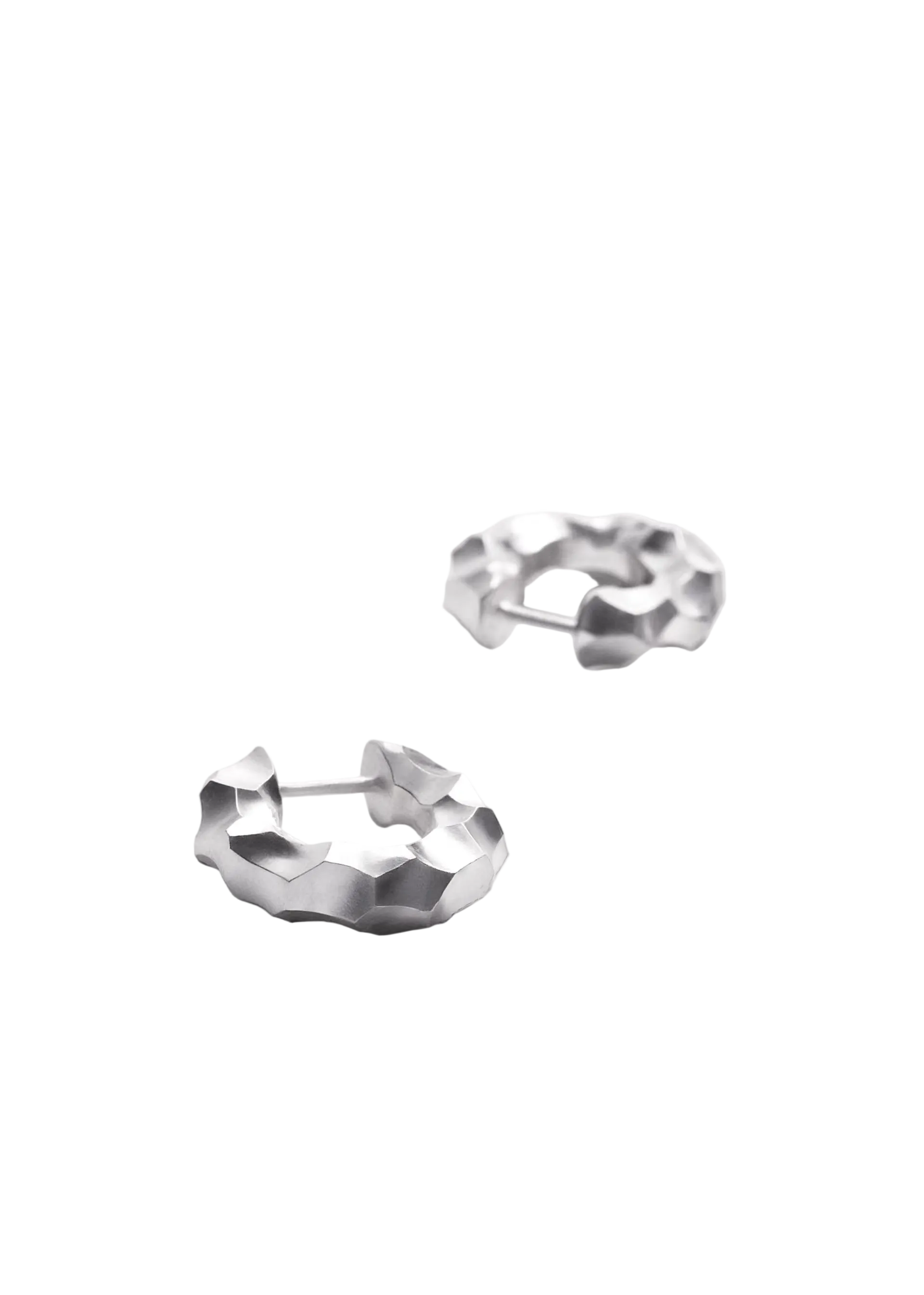 A pair of silver huggie hoop earrings with a textured, faceted geometric design, photographed on a clean white background.