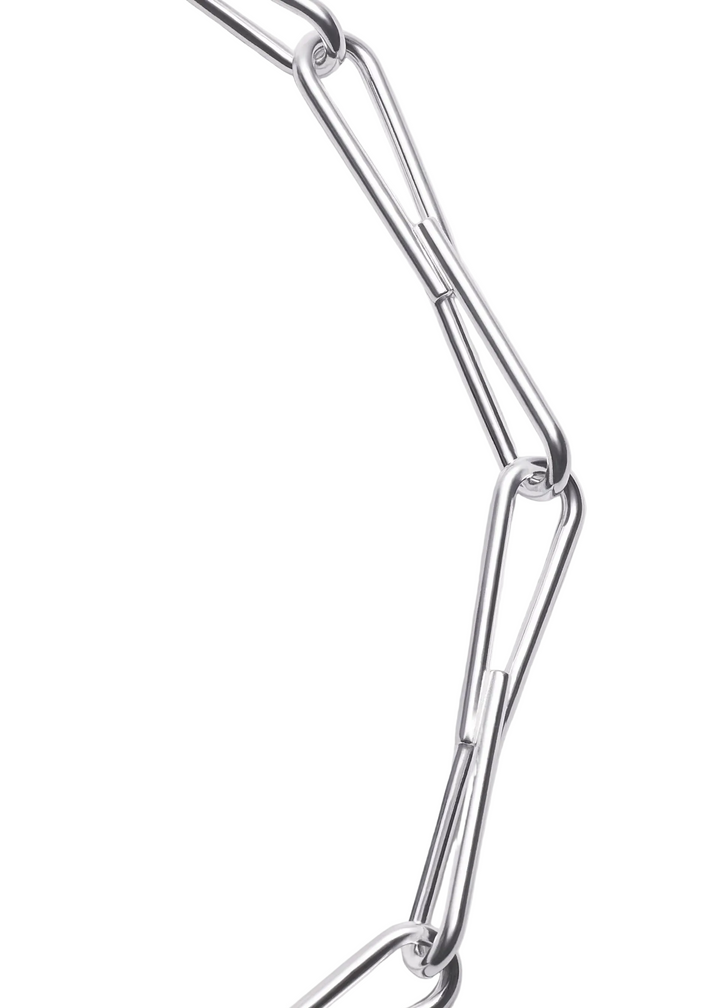 A close-up of a polished silver metal chain with elongated, interlocking links on a plain light gray background.