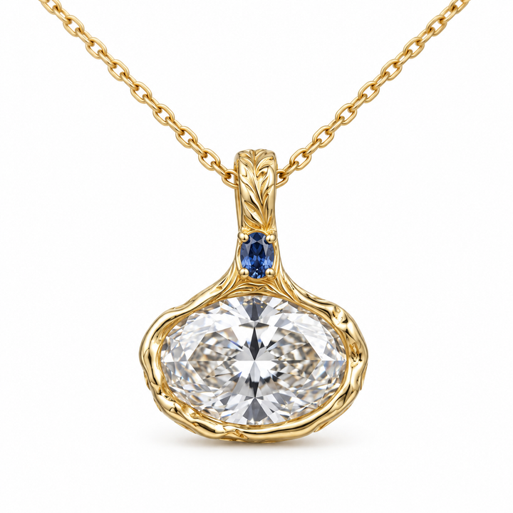 Front view of an oval-cut pendant with a blue accent and botanical gold setting on a white background.